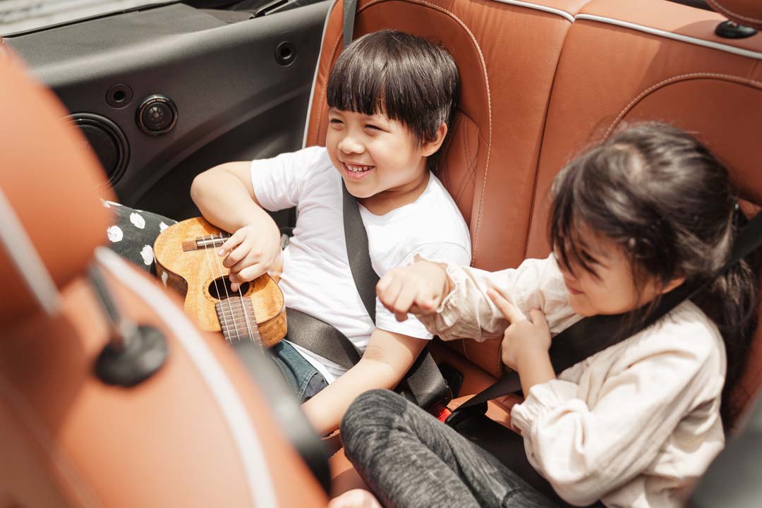 Pair of Asian children sitting in the backseat of a car
