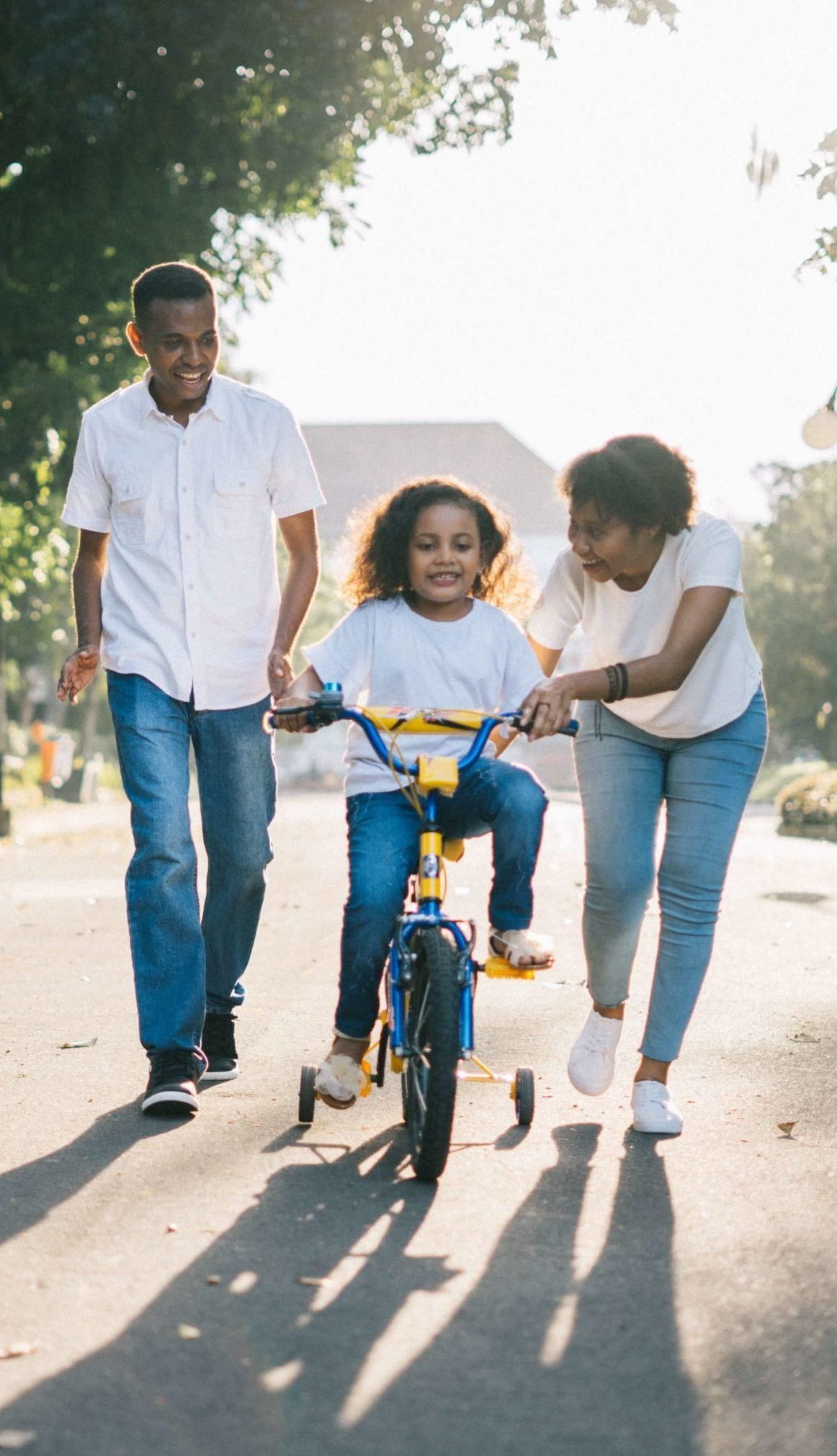 Black couple teaching their daughter how to ride a bike