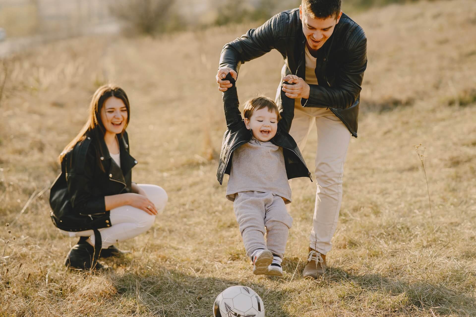 Young parents playing soccer with their child