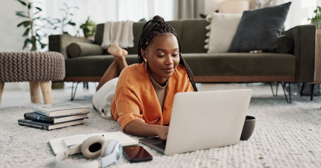 aptop, education and a student black woman on the floor of a living room to study for a test or exam.