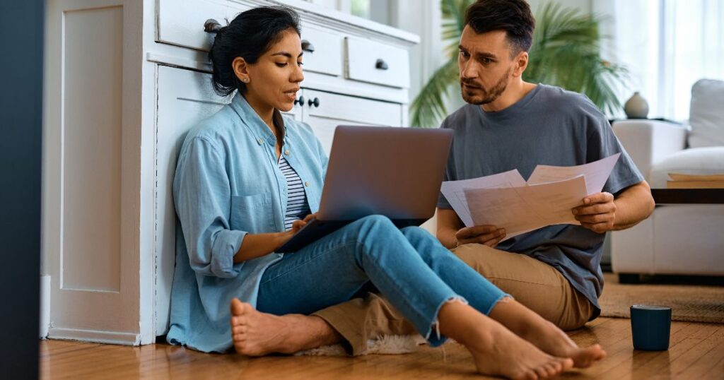 Couple looking at bills on kitchen floor