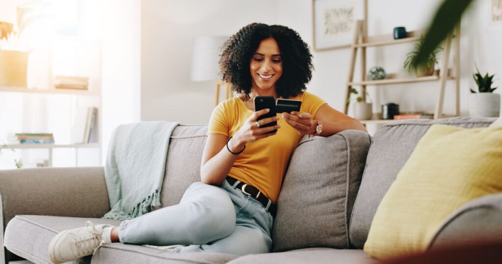 Credit card, happy and woman on sofa with phone for online shopping, web store sale and purchase. Home, relax and person on smartphone for internet payment, digital order and ecommerce in living room